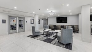 A modern lobby with a seating area, a flat-screen TV, and a glass door entrance.