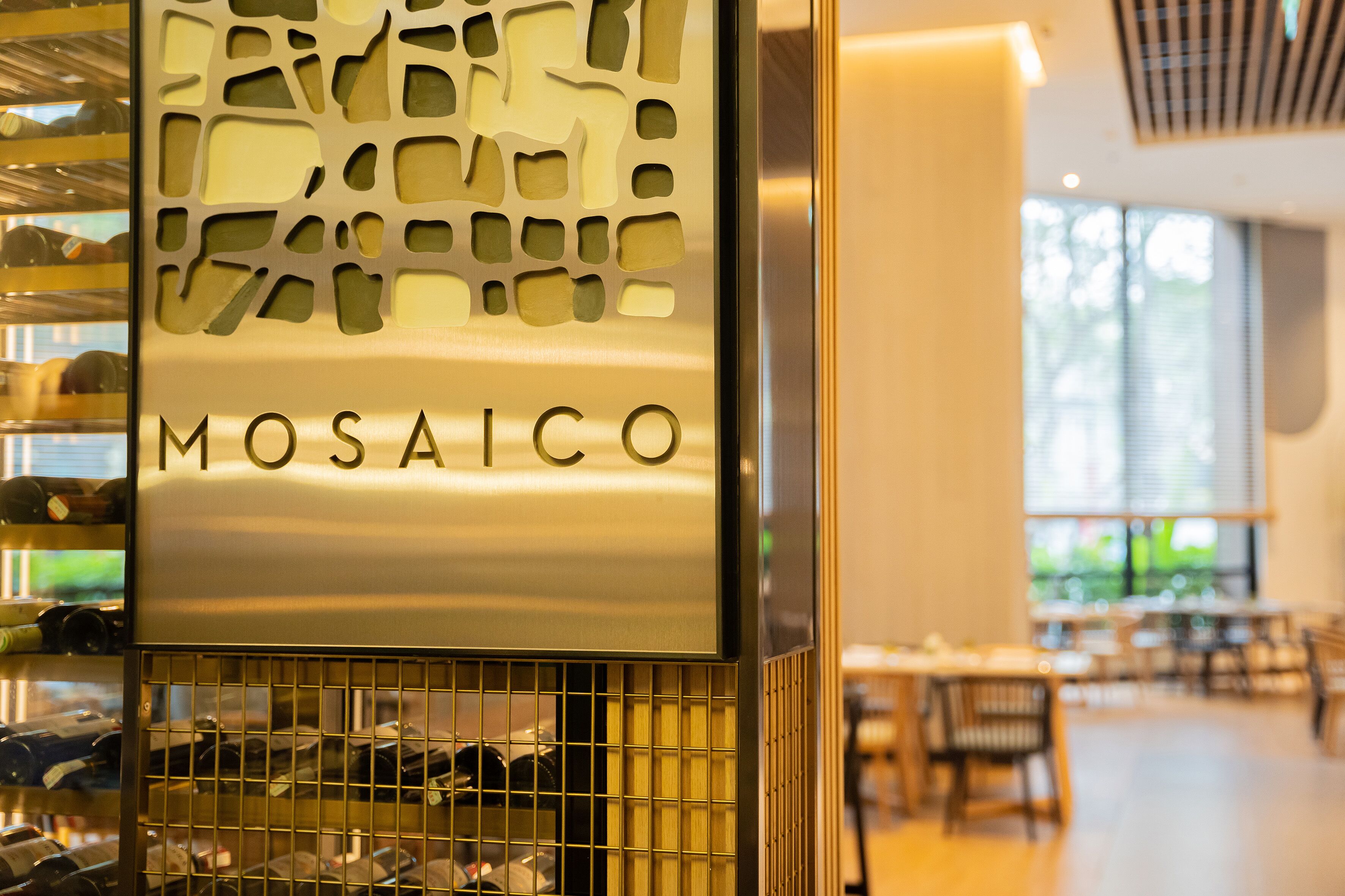 A sign with the name "MOSAICO" in a modern interior setting.