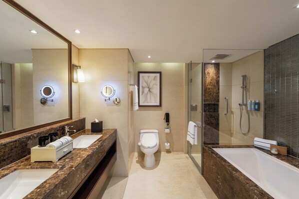 Un baño moderno con un espejo grande, dos lavamanos, un inodoro, ducha y bañera.