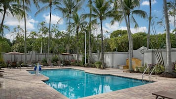 Una piscina al aire libre, sillones reclinables de piscina