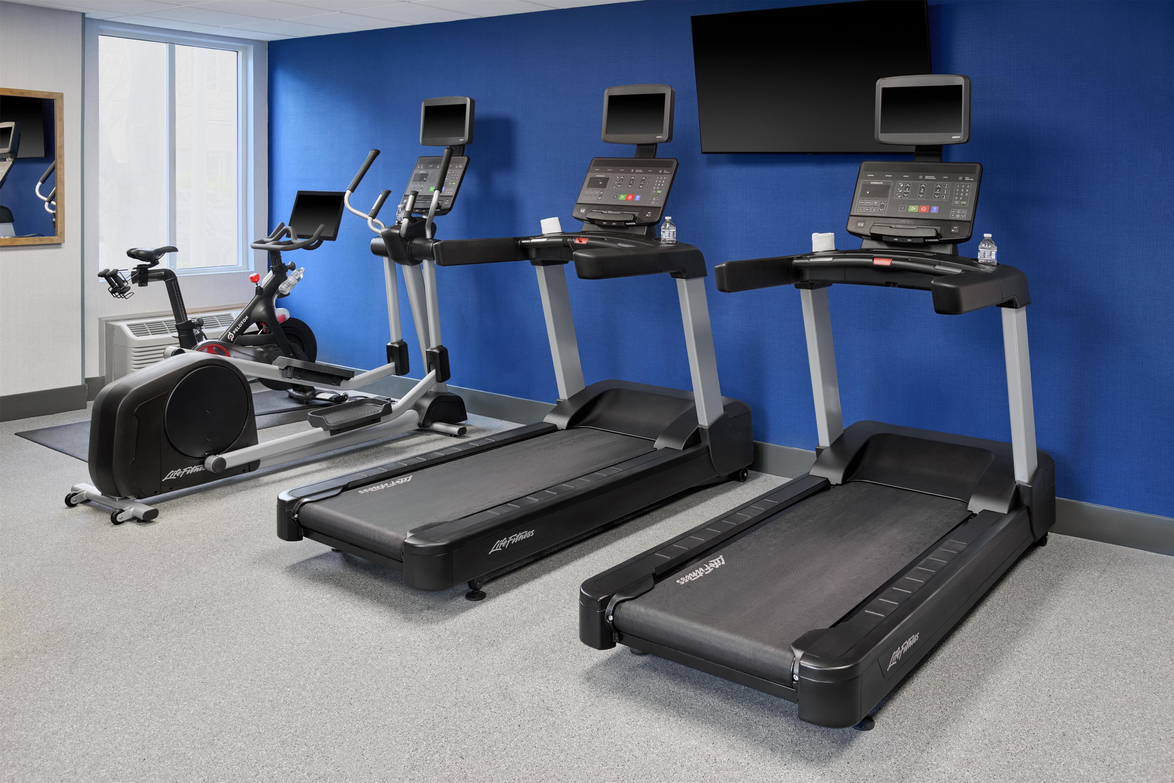 A gym with treadmills, an elliptical, and a stationary bike.