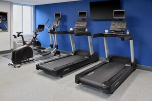 Une salle de sport équipée de tapis de course, d’un vélo elliptique et d’un vélo d’appartement.