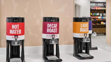 Three coffee machines labeled 'HOT WATER,' 'DECAF ROAST,' and 'LIGHT ROAST' on a counter.
