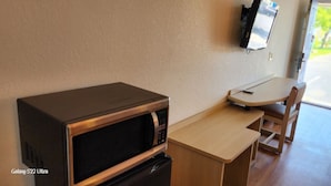 A compact kitchenette with a microwave, a small table, and a chair. - FairBridge Inn Express London (London)