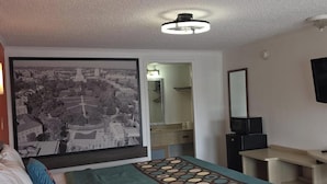 A hotel room with a bed, a television, a desk, and a large window with a cityscape view. - FairBridge Inn Express London (London)