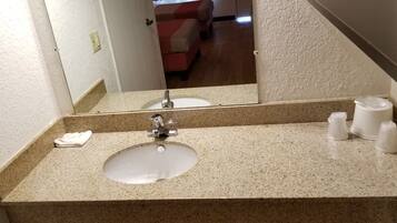 A bathroom with a granite countertop sink, a mirror, and a towel.
