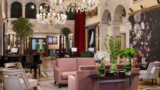 A luxurious lobby with a grand chandelier, plush seating, a grand piano, and a large floral mural. - NH Collection Venezia Grand Hotel Dei Dogi (Venice)