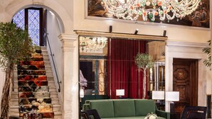 A grand lobby with a staircase, a chandelier, a green sofa, and a coffee table. - NH Collection Venezia Grand Hotel Dei Dogi (Venice)