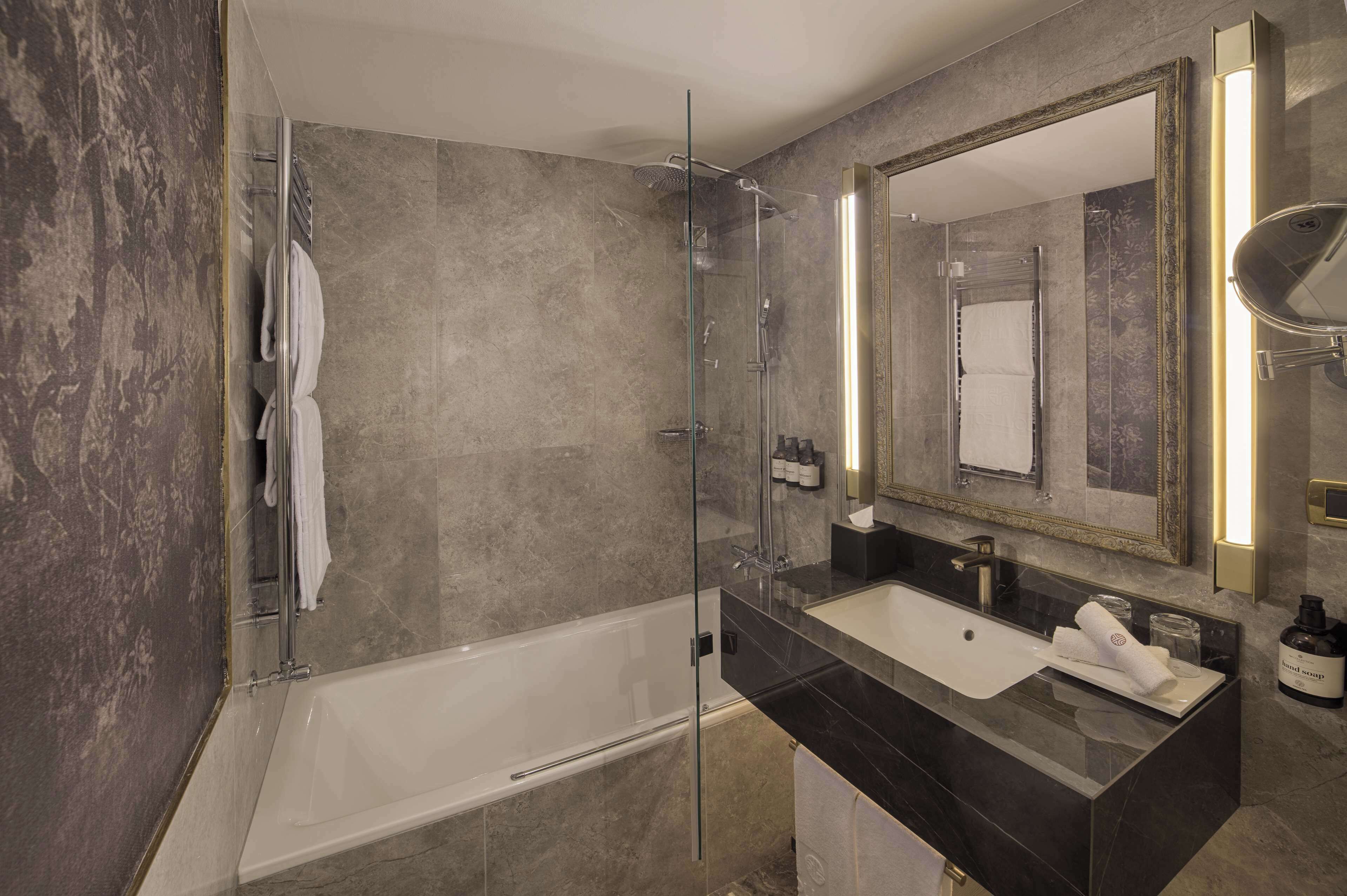 A modern bathroom with a glass-enclosed shower, a standalone bathtub, and a vanity with a large mirror.