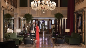 A grand lobby with a large chandelier, green sofas, and a red curtain. - NH Collection Venezia Grand Hotel Dei Dogi (Venice)