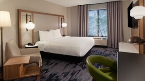A hotel room with a bed, a desk, a chair, a lamp, and a window with curtains. - Fairfield Inn & Suites by Marriott Charleston (South Charleston)