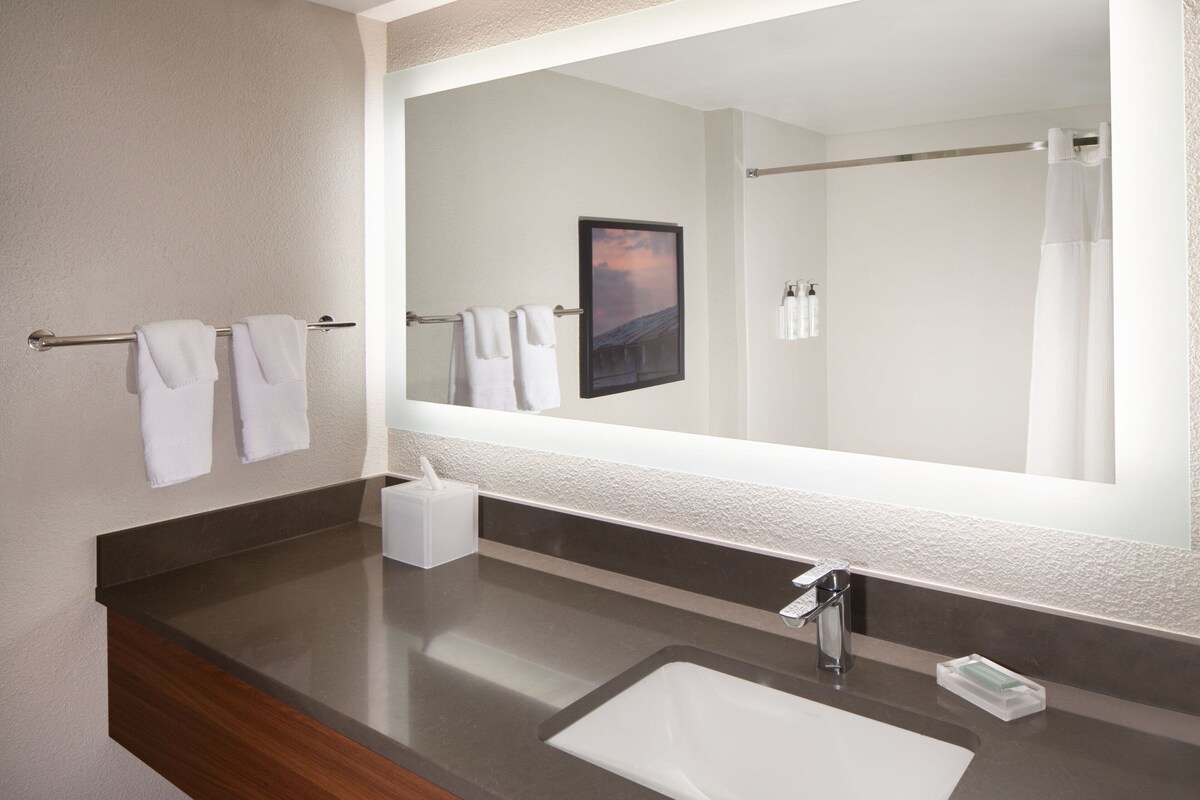 Un baño moderno con un espejo grande, un lavabo y un perchero para toallas.