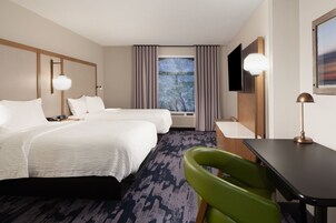 Habitación de hotel con dos camas, un escritorio, una silla, un televisor y una ventana con cortinas.