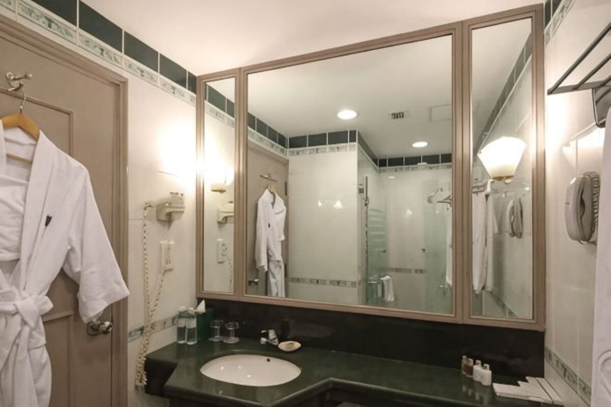 Ein Badezimmer mit großem Spiegel, Waschbecken und Bademantelhalter.