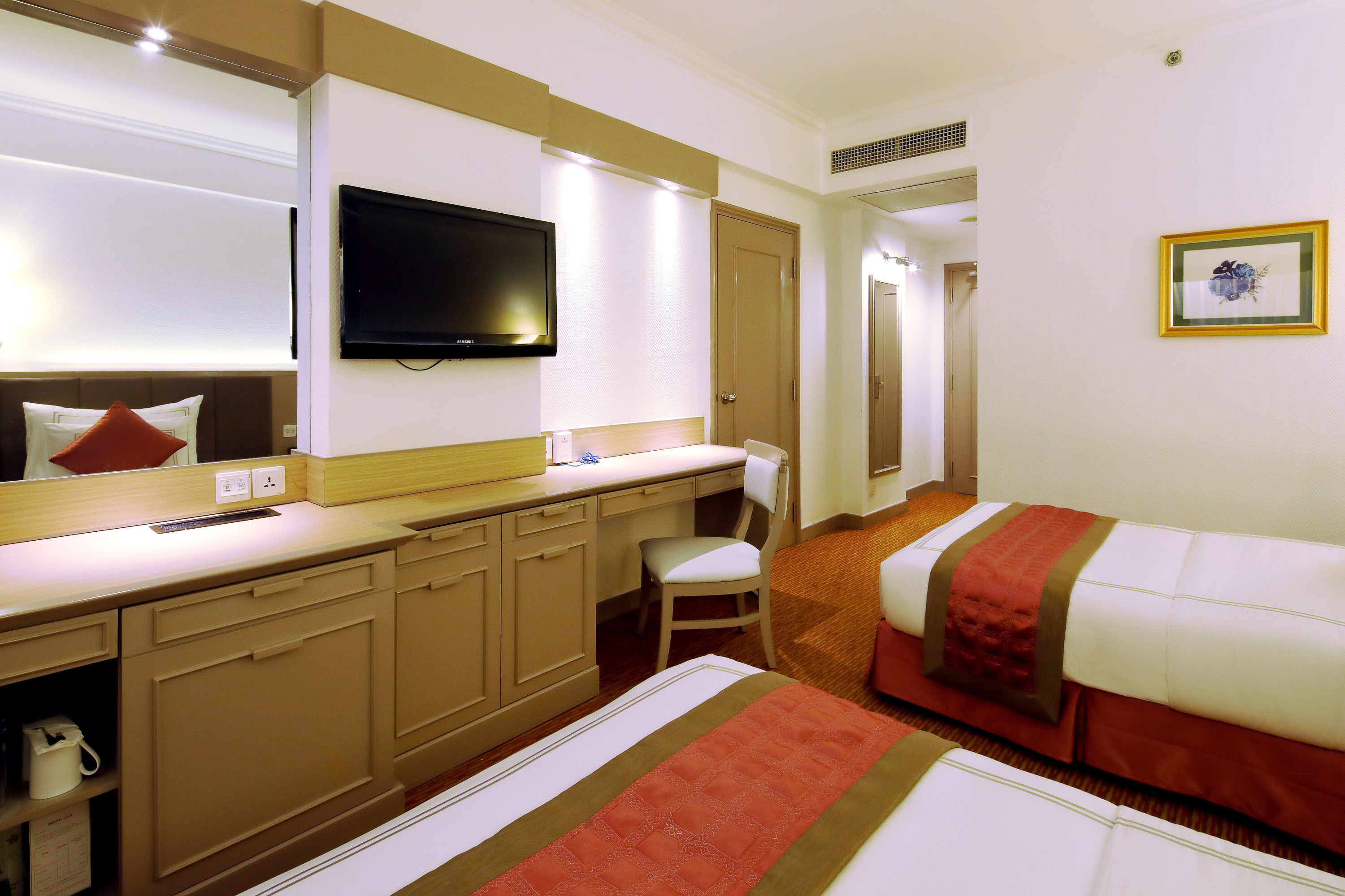 A hotel room with a bed, a desk, a chair, a television, and a door.