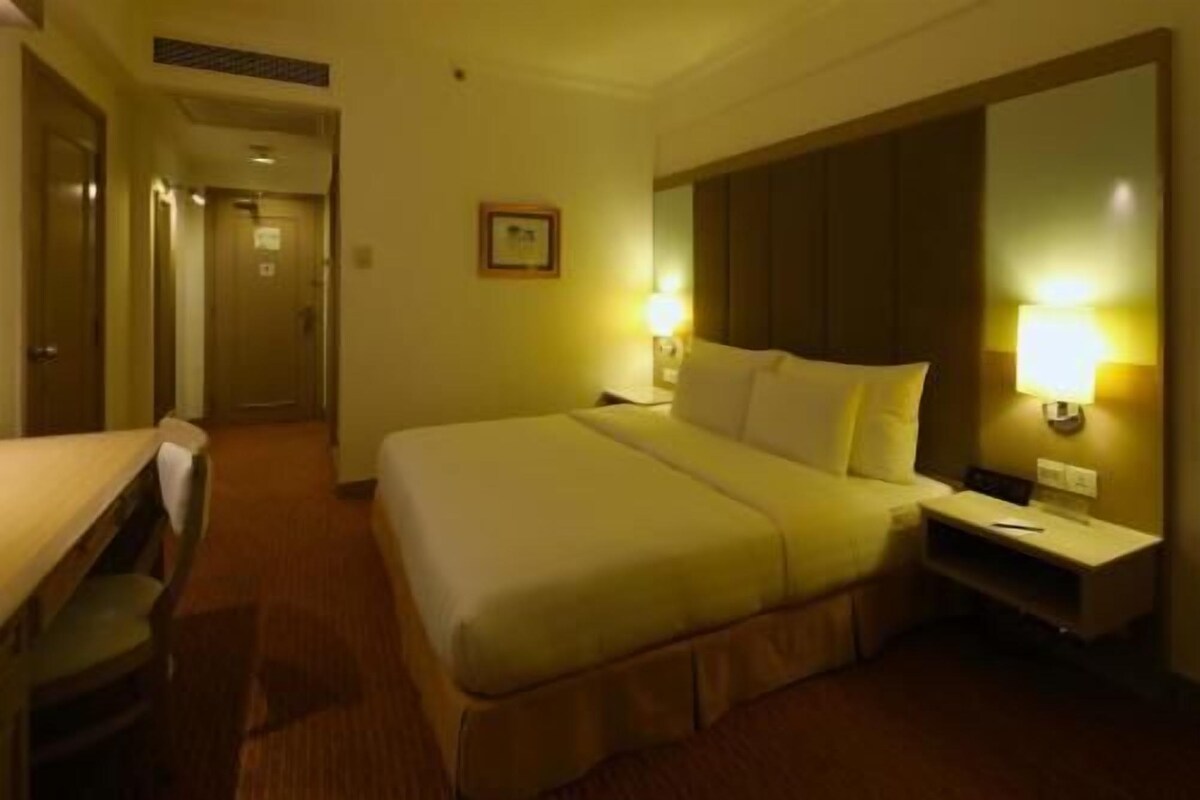 Une chambre d’hôtel comprenant un lit, une table de chevet, une lampe et une porte donnant sur une autre pièce.