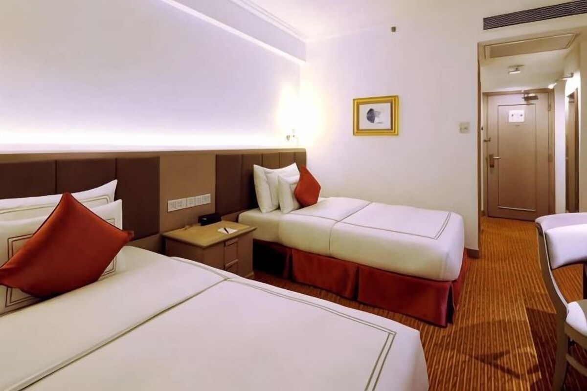 Ett hotellrum med två sängar, ett nattduksbord, en lampa och en dörr.