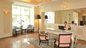 A well-lit room with a glass desk, striped chairs, and a large mirror. - Sunway Hotel Hanoi (Hanoi)