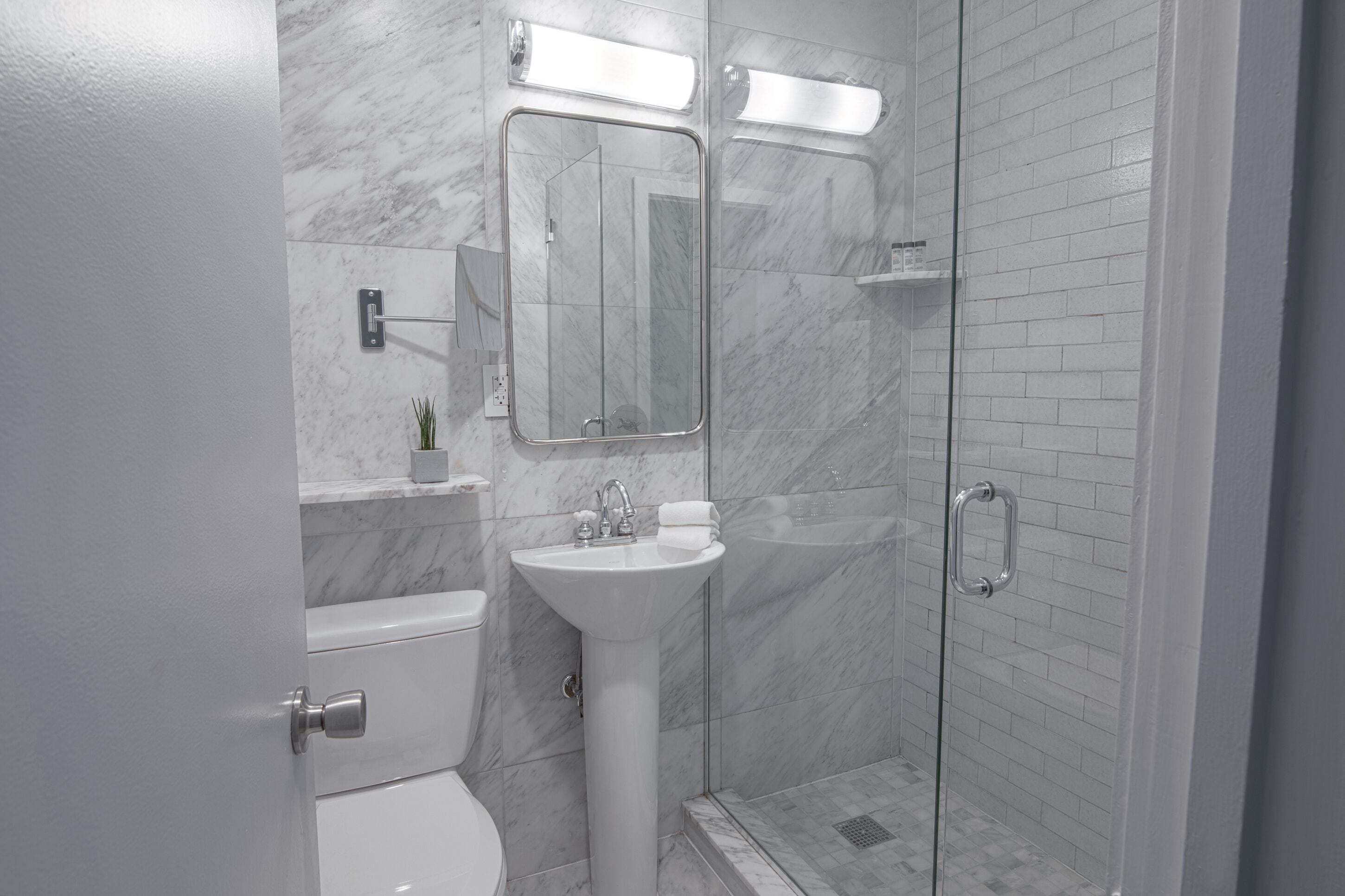 A modern bathroom with a toilet, sink, and glass-enclosed shower.