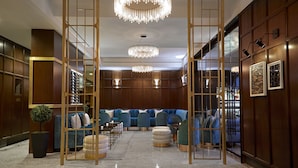A modern lobby with a seating area, chandeliers, and wooden paneling.