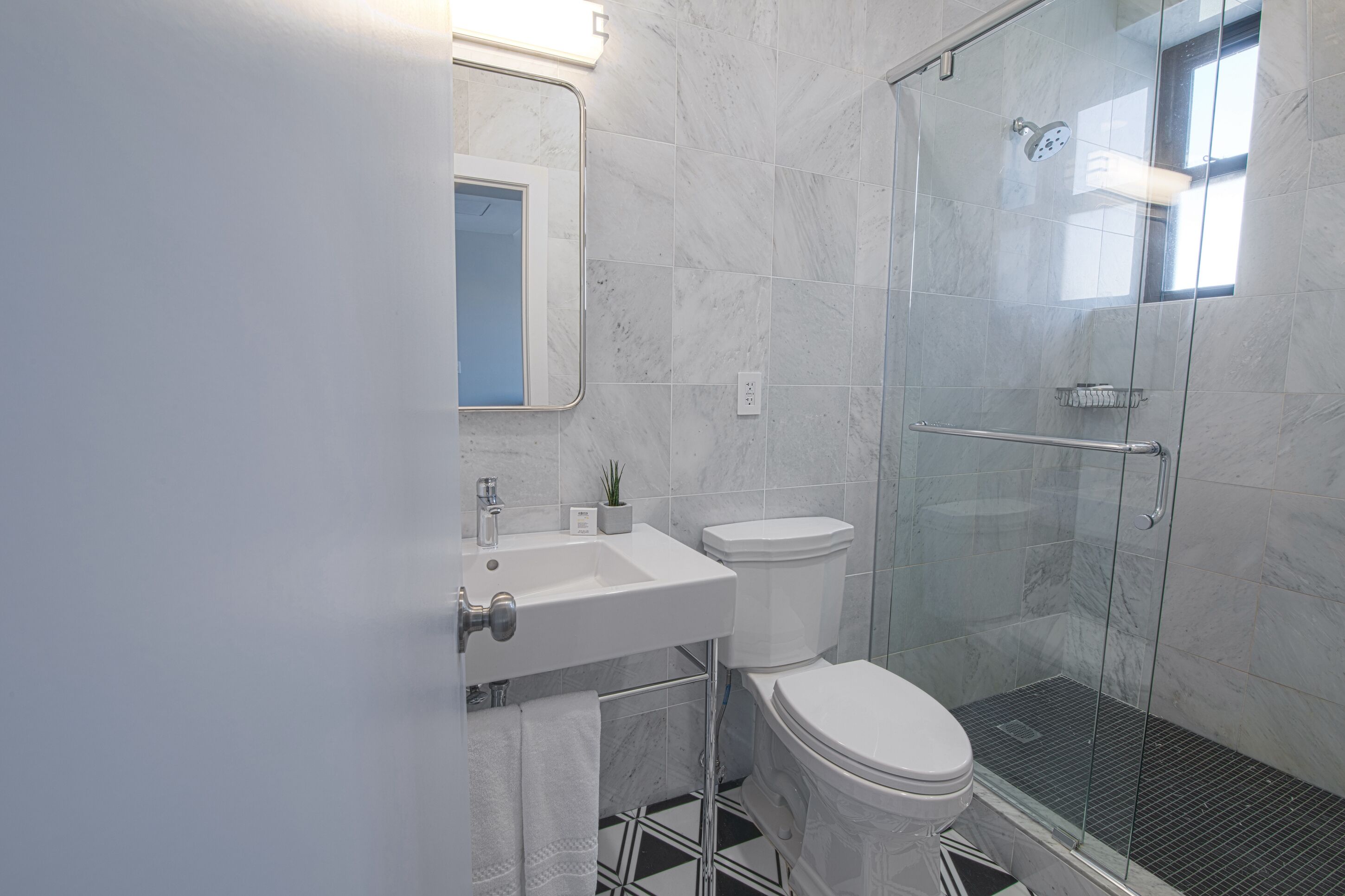 A modern bathroom with a glass-enclosed shower, a white sink, and a toilet.