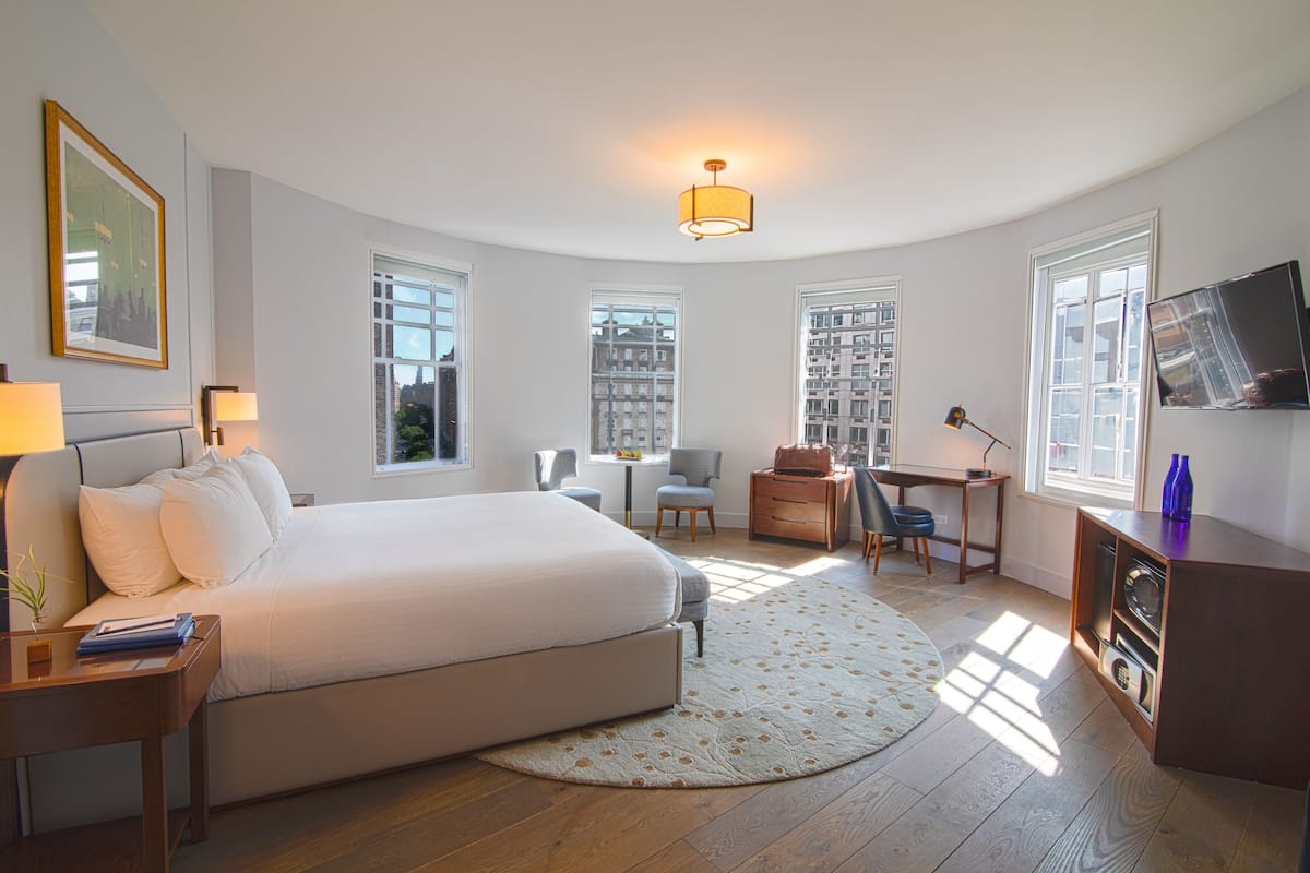 Una habitación de hotel moderna con una cama grande, un escritorio, una silla y un televisor.