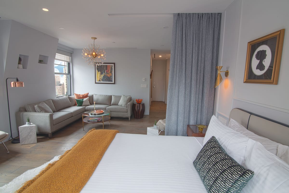 Una habitación de hotel moderna con una cama grande, un sofá, una mesa de centro y una araña.