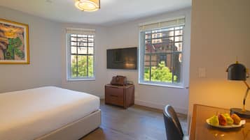 A bedroom with a bed, a nightstand, a desk with a lamp, and a TV.