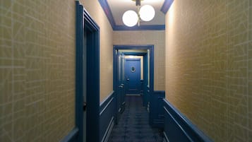 Un estrecho pasillo con paredes estampadas y detalles azules, que conduce a una puerta al final.
