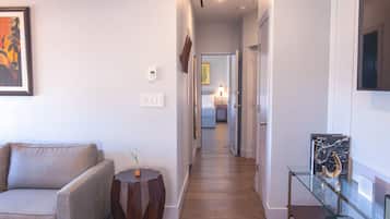 A hallway with a sofa, a small table with a plant, a glass display case with an object, and a door leading to another room.