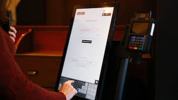 En person bruger en berøringsskærm-automat til at finde en reservation.