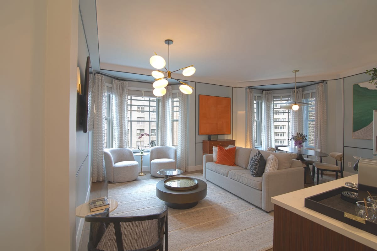 Una sala de estar moderna con un sofá, sillones, una mesa de centro y un comedor con mesa y sillas.