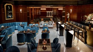 A modern lounge with blue seating, a bar area, and a large mirror.