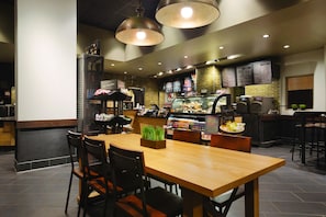 A restaurant interior with a wooden table and chairs, a menu board, and a food display counter. - Embassy Suites by Hilton Atlanta at Centennial Olympic Park (Atlanta)