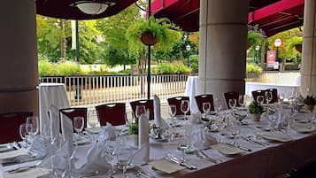 A table set for a formal outdoor dining experience with a view of a garden and street.