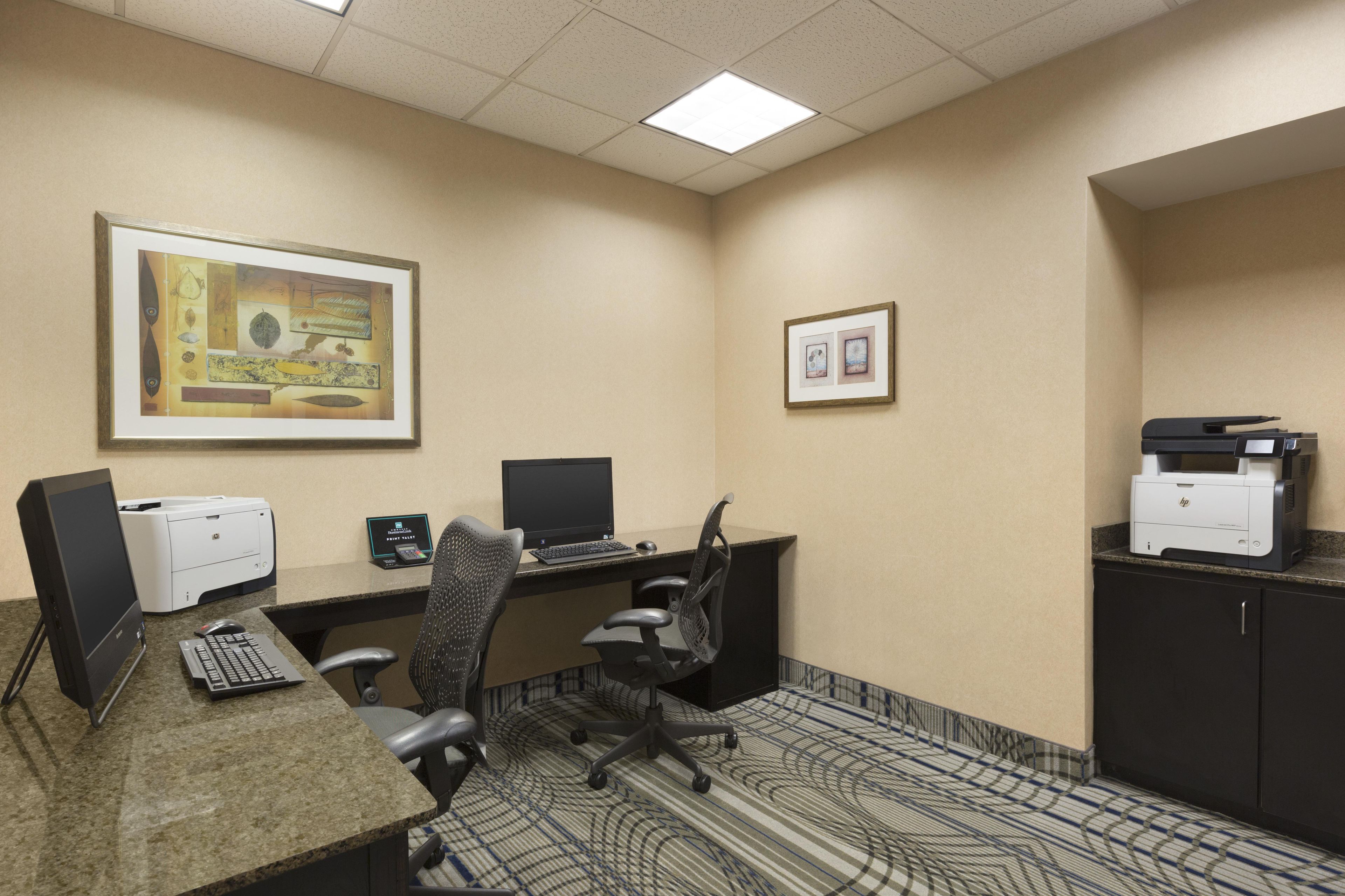 A conference room with a desktop computer, a printer, and a framed artwork on the wall.