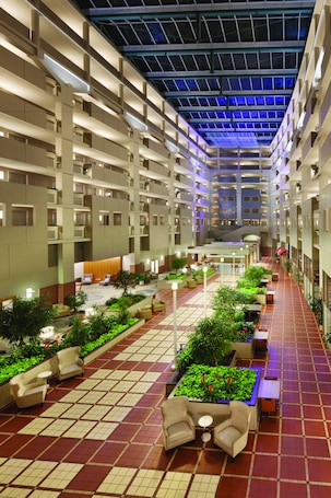 A spacious indoor atrium with a central open area, multiple levels of balconies, and a variety of seating arrangements.