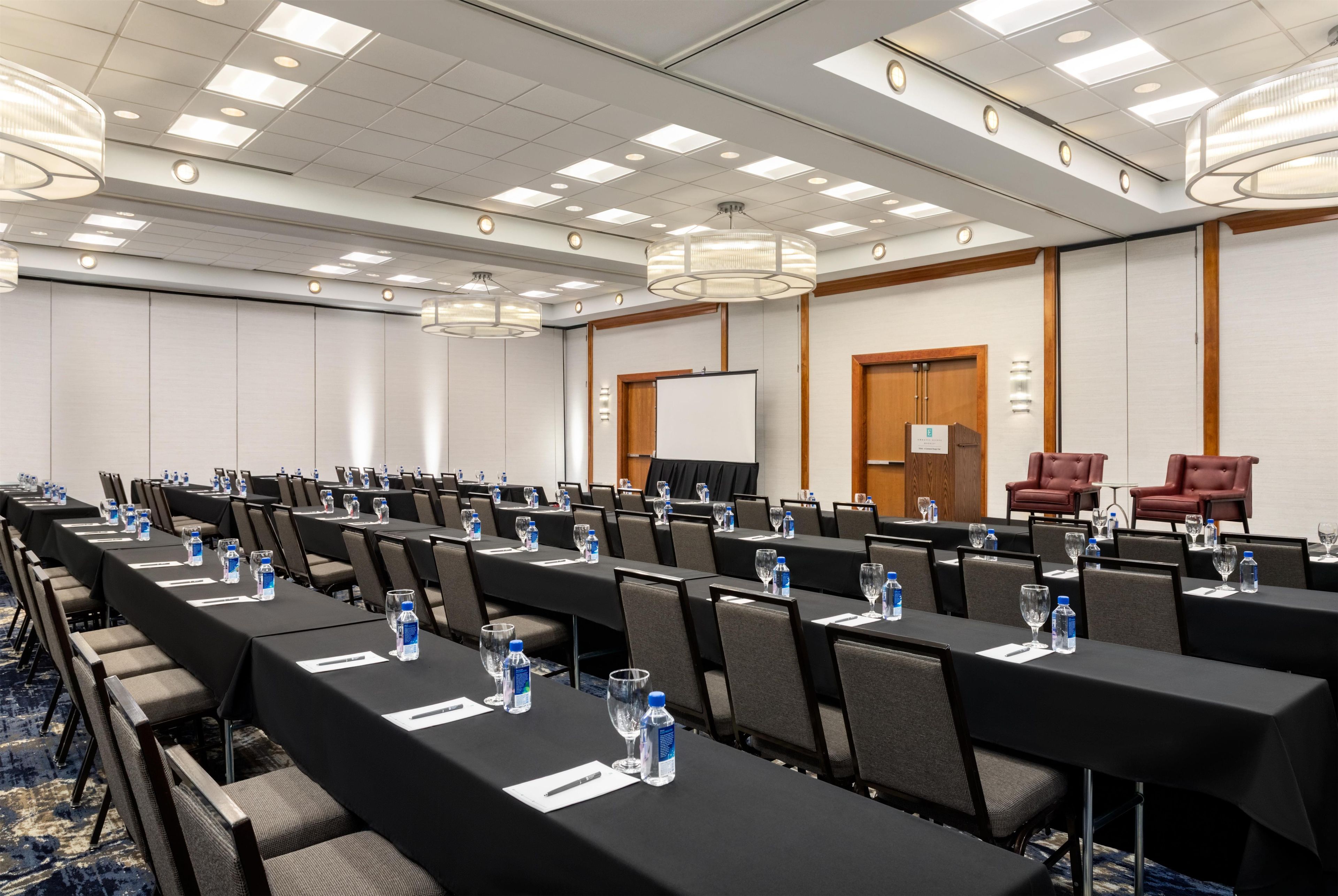 A conference room with rows of tables, chairs, and water bottles.
