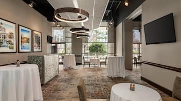 A hotel lobby with round tables, a reception desk, and framed pictures on the wall.
