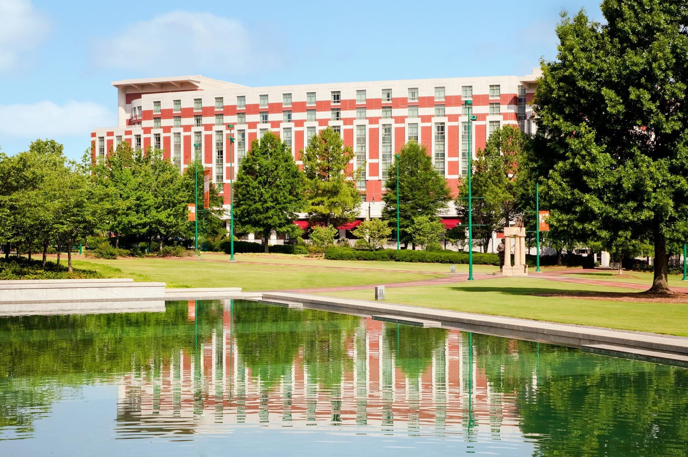 A building with a red and white facade, surrounded by a well-maintained lawn and a reflective water feature.