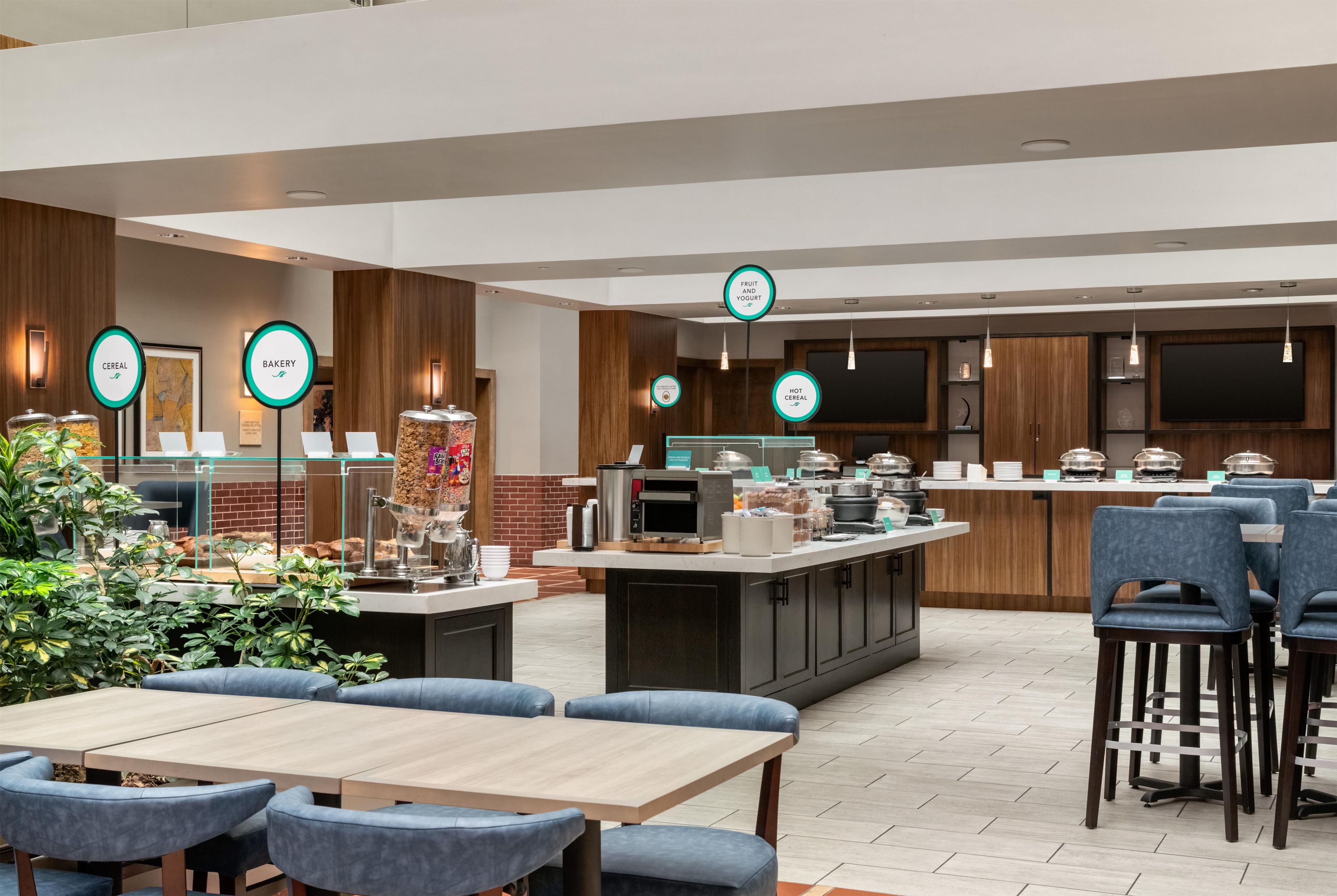 A modern restaurant with a central island, seating area, and various food stations.