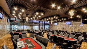 Une grande salle de conférence dotée de nombreuses tables et chaises, équipée d’écrans et présentant un design moderne au niveau du plafond.