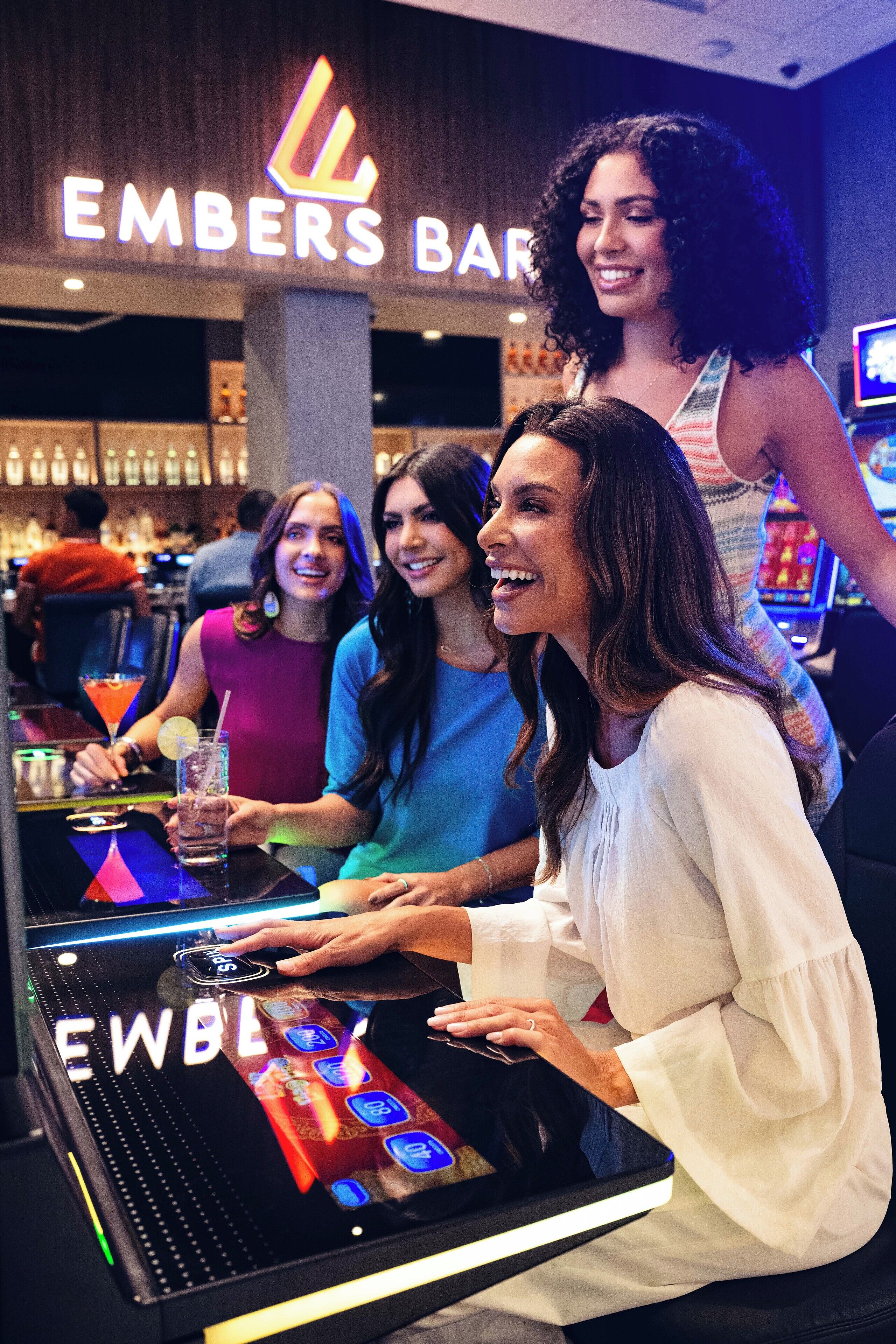 A bar area with a digital screen, bar stools, and a sign reading 'EMBERS BAR'.