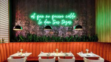 Interior de un restaurante con letrero de neón, cabinas y mesas.