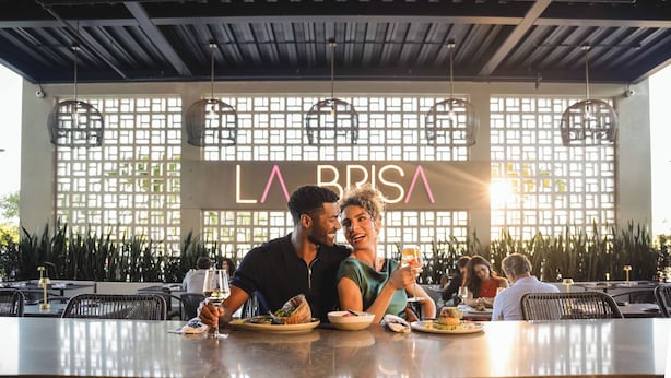 Un espace de restauration intérieur avec des tables, des chaises et des luminaires suspendus.