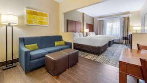 A hotel room with a bed, a sofa, a coffee table, a desk, and a lamp. - Comfort Suites Keeneland (Lexington)