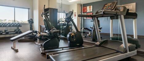 Ein Fitnessstudio mit Laufbändern, Hanteln und Trainingsgeräten.