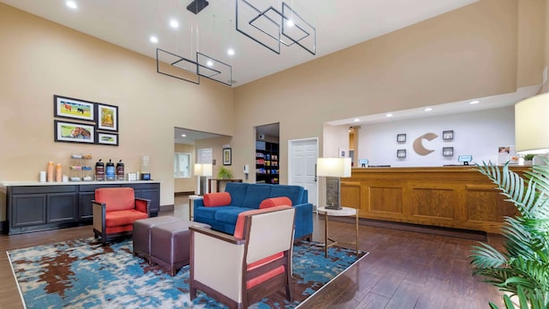A hotel lobby with a reception desk, seating area, and a large mirror. - Comfort Suites Keeneland (Lexington)