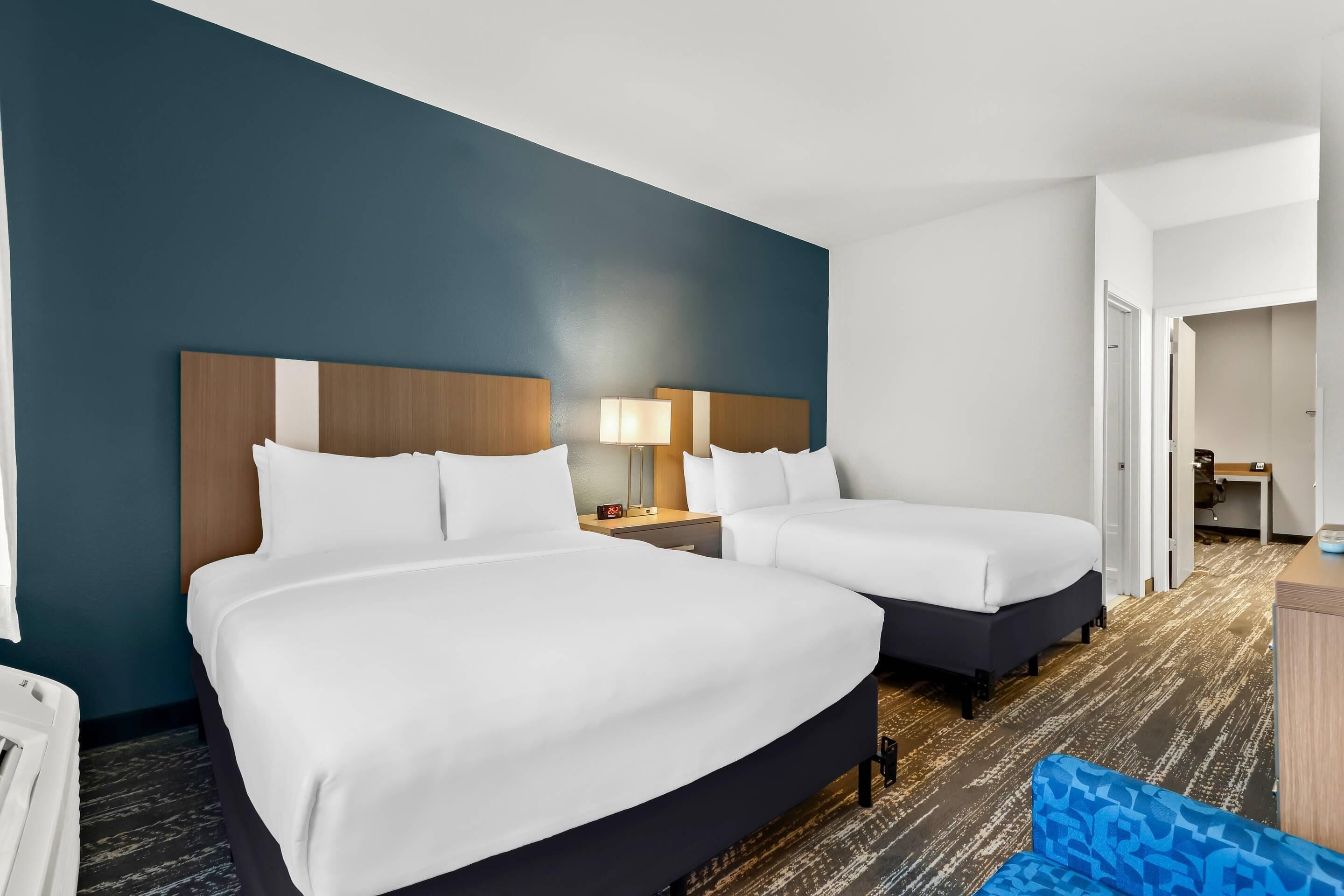 Hotellihuone, jossa on kaksi sänkyä, työpöytä ja tuoli.