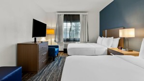 A hotel room with two beds, a TV, a desk, and a window with curtains. - Clarion Suites Anchorage Downtown (Anchorage)
